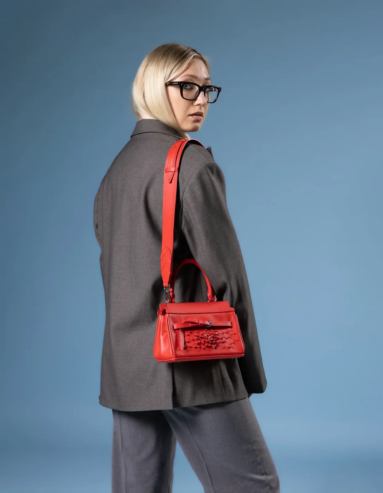 A model standing with a red handmade handbag