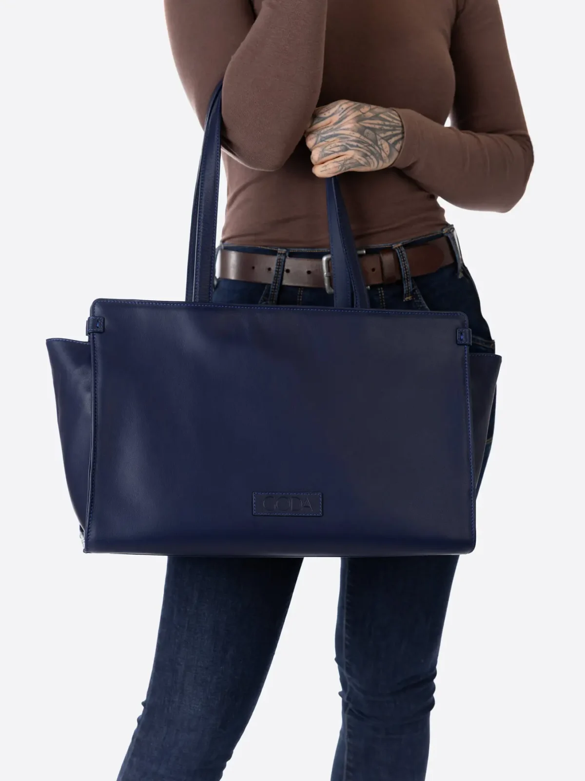 Modelis laikantis tamsiai mėlyna didelę rankinę